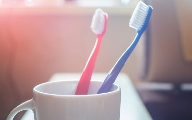 Two Toothbrushes Inside A White Ceramic Cup
